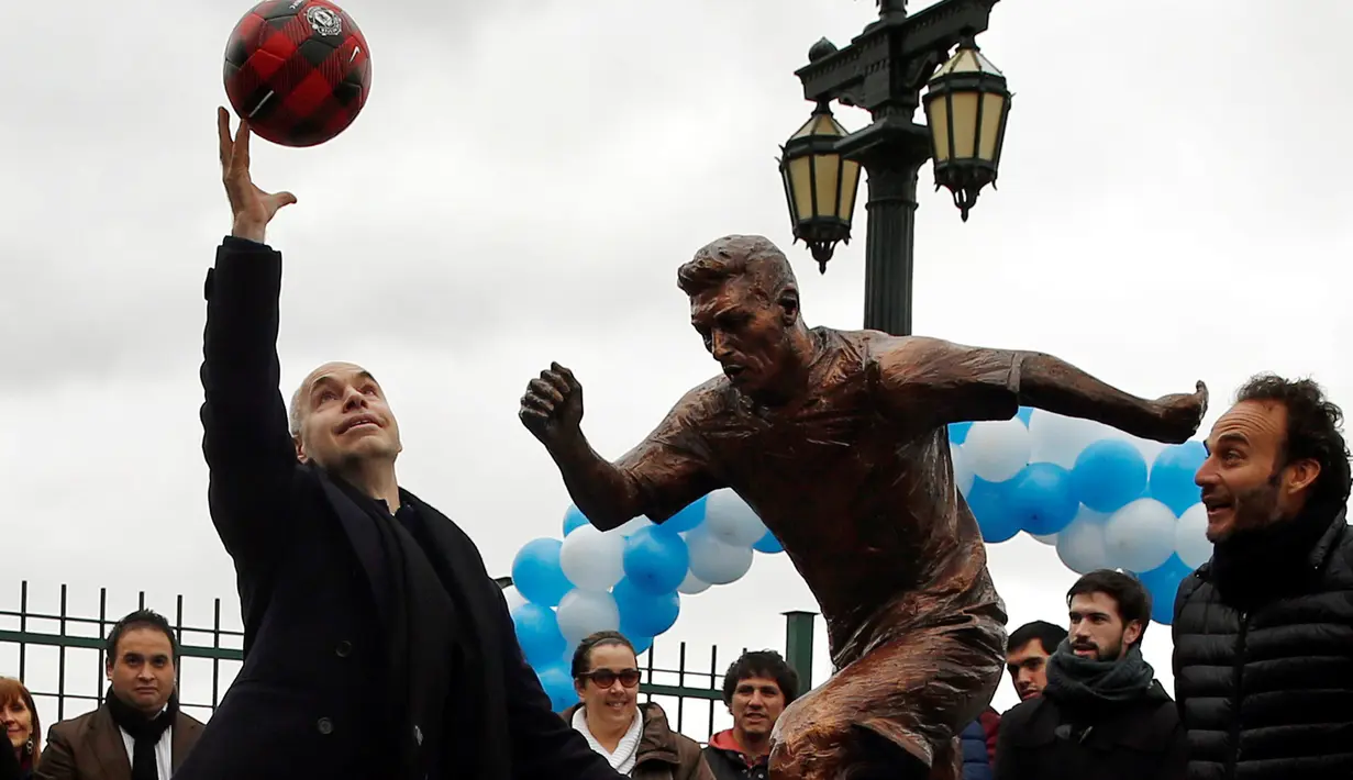 Wali Kota Horacio Larreta Rodriguez melempar bola di depan patung Lionel Messi yang baru diresmikan di Buenos Aires, Argentina, Selasa (28/6). Patung itu guna membujuk Messi membatalkan keputusan pensiun yang sudah diambilnya. (REUTERS/Marcos Brindicci)
