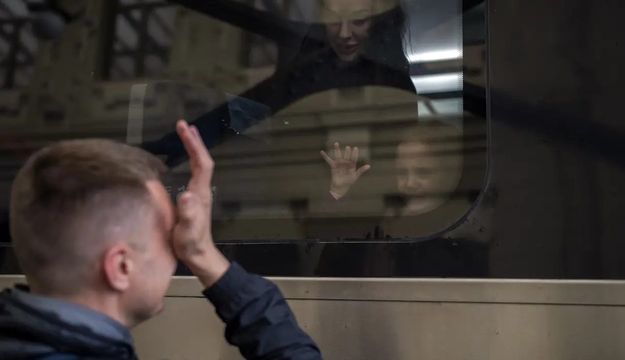 Nicolai (41) dari Ukraina menangis saat mengucapkan selamat tinggal kepada putrinya Elina (4) dan istrinya Lolita dalam kereta menuju Polandia untuk melarikan diri dari perang di stasiun kereta di Lviv, Ukraina, 15 April 2022. Pengungsi didominasi wanita dan anak-anak. (AP Photo/Emilio Morenatti)