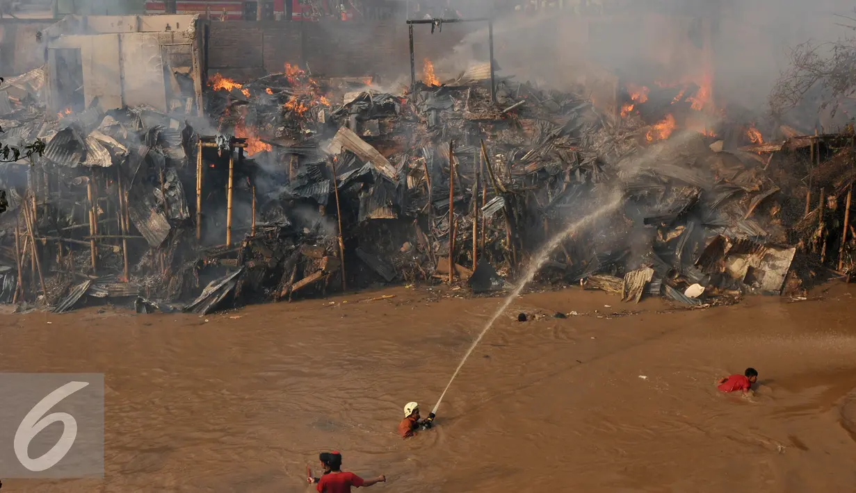 Petugas pemadam berupaya menyemprotkan air saat terjadinya kebakaran yang melanda rumah hunian semi permanen di bantaran sungai anak kali ciliwung, Kawasan Kampung Berland, Jakarta, Rabu (2/9/2015). (Liputan6.com/Johan Tallo)