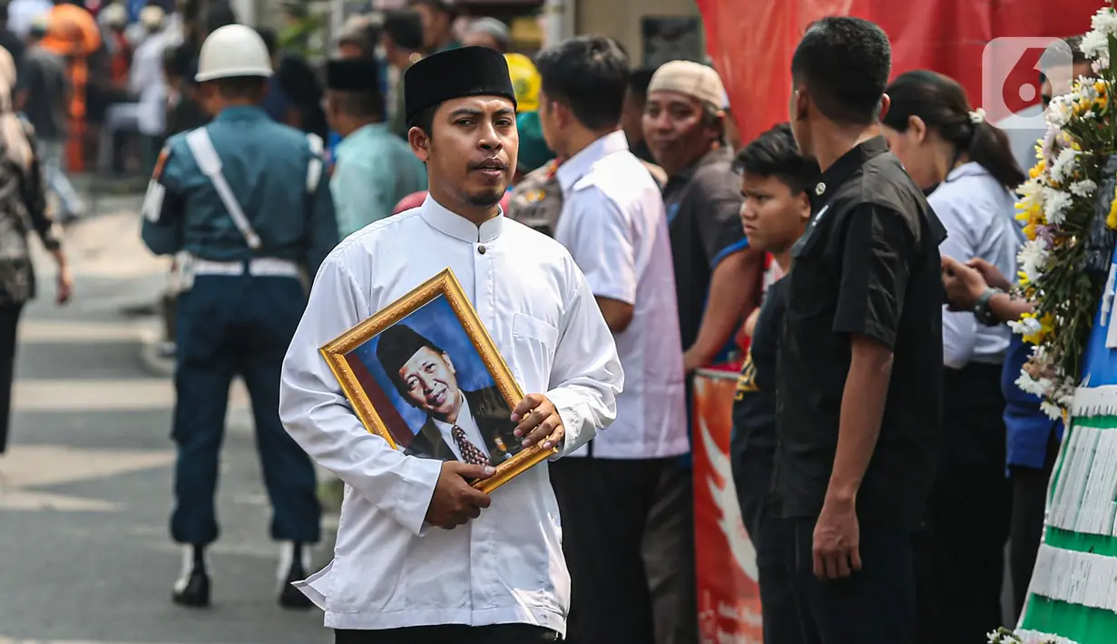 Kerabat membawa foto almarhum Wakil Presiden ke-9 Republik Indonesia, Hamzah Haz di Jalan Tegalan, Matraman, Jakarta, Rabu (24/7/2024). (Liputan6.com/Angga Yuniar)