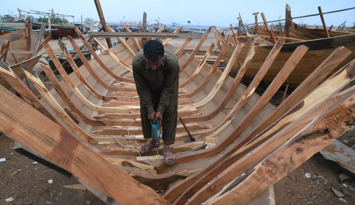 Tukang kayu Pakistan membuat kapal penangkap ikan di sebuah pelabuhan di Karachi (3/4). Pembuatan kapal buatan Pakistan menghasilkan ratusan kapal setiap tahun untuk memenuhi permintaan industri perikanan setempat. (AFP Photo/Asif Hassan)