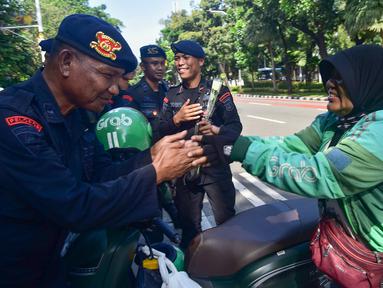 Pengemudi ojek daring/online (ojol) memberikan bunga mawar kepada salah satu personel kepolisian dari unsur Korps Brigade Mobil (Brimob) di sekitar kawasan Monumen Nasional, Jakarta, Selasa (2/9/2025). (merdeka.com/Arie Basuki)