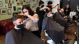 Para pria memotong rambut di barber shop di Melbourne, Australia, Senin (19/10/2020). Warga Kota Melbourne, pada Senin (19/10), akhirnya bisa bernafas lega saat sejumlah pembatasan dilonggarkan setelah menjalani lockdown tahap keempat yang ketat selama sekitar 100 hari. (William WEST/AFP)