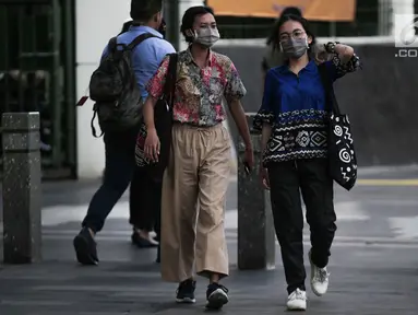 Dua wanita berjalan mengenakan masker pelindung untuk menghindari polusi udara buruk di Jakarta, Rabu (17/7/2019). Dinkes DKI menyarankan masyarakat untuk menggunakan masker saat beraktivitas untuk mencegah dampak polusi udara pada tubuh. (Liputan6.com/Faizal Fanani)