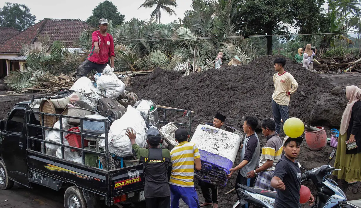 Kerusakan rumah dan fasilitas umum ini tidak hanya diakibatkan oleh awan panas guguran, melainkan juga terjangan banjir lahar yang terjadi dalam tiga hari terakhir. Tampak dalam foto, warga menyelamatkan barang-barang dari sebuah rumah yang hancur akibat aliran piroklastik Gunung Semeru di Desa Supiturang, Lumajang, Jawa Timur, pada Jumat 21 November 2025. (Agus Harianto/AFP)