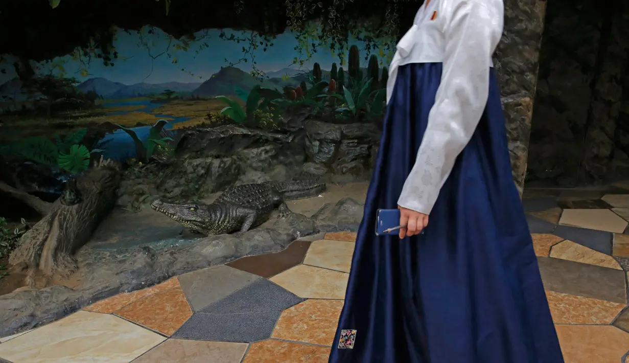 Seorang anggota staf dari kebun binatang berdiri di samping model replika buaya di Kebun Binatang di Pyongyang, Korea Utara (15/9). (AP Photo/Kin Cheung)