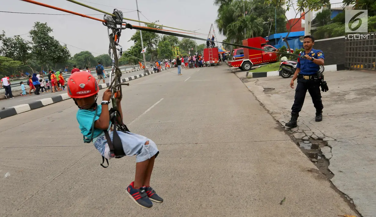 Seorang anak sedang bermain flying fox yang digelar Dinas Pemadam Kebakaran saat Car Free Day di Danau Sunter, Jakarta Utara, Minggu (28/1). (Liputan6.com/Fery Pradolo)