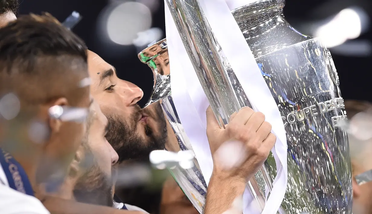 Penyerang Real Madrid, Karim Benzema mencium piala usai memenangkan pertandingan Liga Champions di Stadion Cardiff, Wales (3/6). (AFP Photo/Filippo Monteforte)