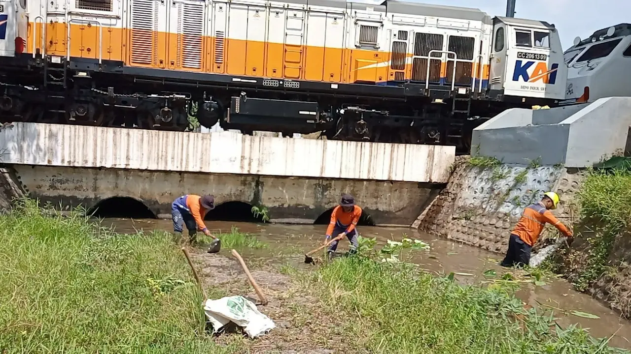Petugas KAI Daop 9 Jember membersihkan sendimentasi lumpur di sungai yang berada di emplasemen stasiun ketapang, Banyuwangi,(Istimewa)