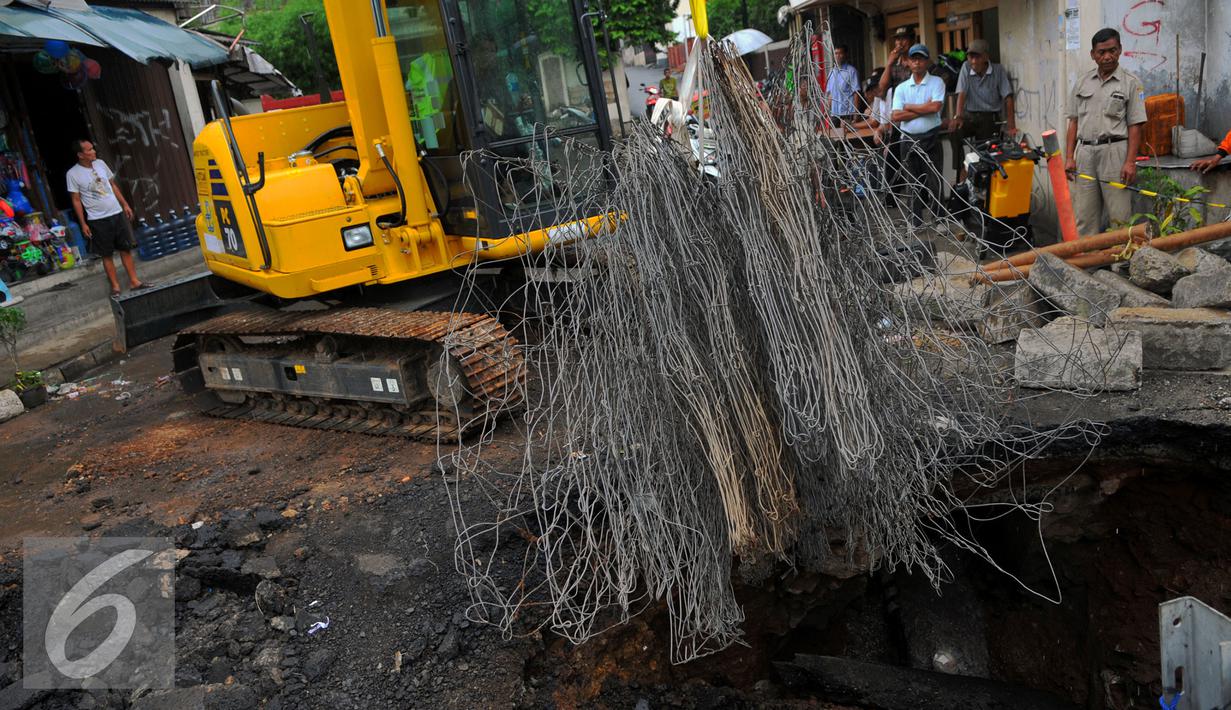 Alat berat mengangkat besi Jembatan Inspeksi Kali Grogol yang ambles di Komplek Hankam, Slipi, Jakarta, Senin (21/3). Dinas Pemprov DKI sedang melakukan perbaikan di kawasan depan Komplek HANKAM slipi Jakarta Barat. (Liputan6.com/Faisal R Syam)