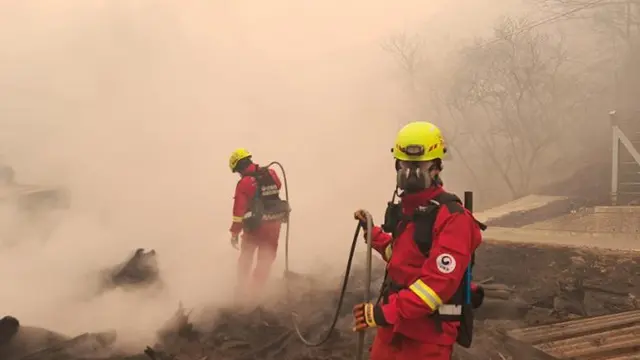 Petugas pemadam kebakaran berusaha memadamkan kebakaran hutan di sebuah desa di Sinan-myeon, Sancheong County, Provinsi Gyeongsang Selatan, 23 Maret 2025. (Yonhap)