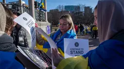 Pengunjuk rasa membagikan spanduk untuk memperingati tahun kedua invasi Rusia ke Ukraina dan sepuluh tahun Rusia mencaplok Krimea di Boston Common, Boston, Massachusetts, 24 Februari 2024. (Joseph Prezioso/AFP)