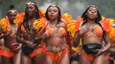 Penari karnaval menari di tengah hujan selama parade hari pertama Karnaval Notting Hill di London barat, Minggu (26/8). Penari mengenakan kostum seksi dan riasan warna-warni saat menggelar karnaval Notting Hill. (AFP/Daniel LEAL-OLIVAS)