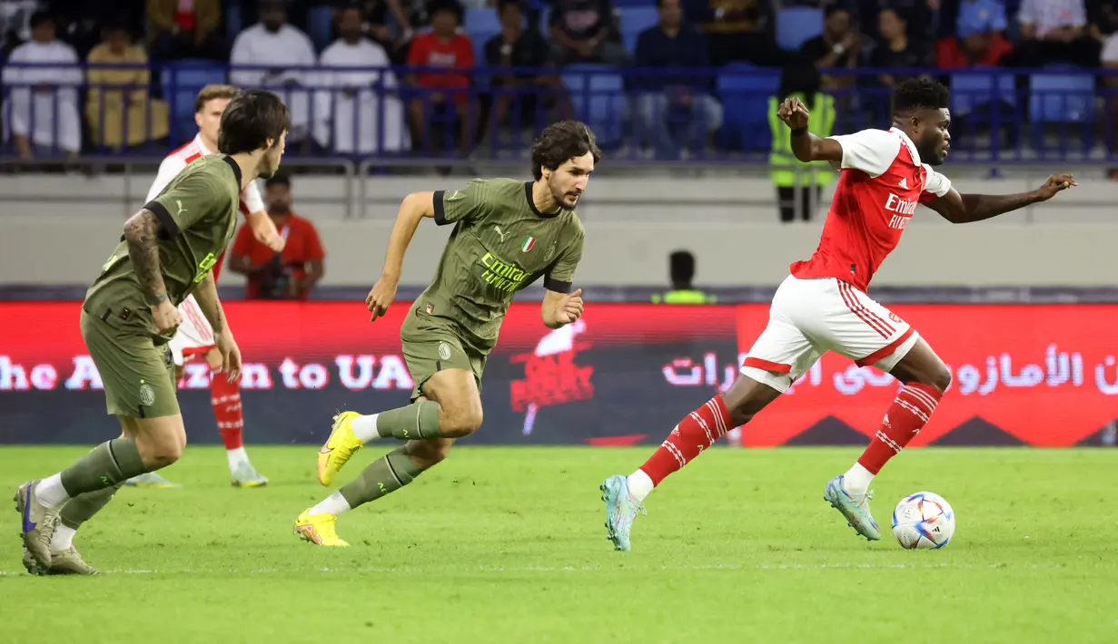 Gelandang Arsenal, Thomas Partey membawa bola dari kejaran gelandang AC Milan, Yacine Adli dan Sandro Tonali selama pertandingan Dubai Super Cup 2022 di di stadion al-Maktoum di Uni Emirat Arab (13/12/2022). Arsenal menang tipis atas AC Milan dengan skor 2-1. (AFP/Karim Sahib)