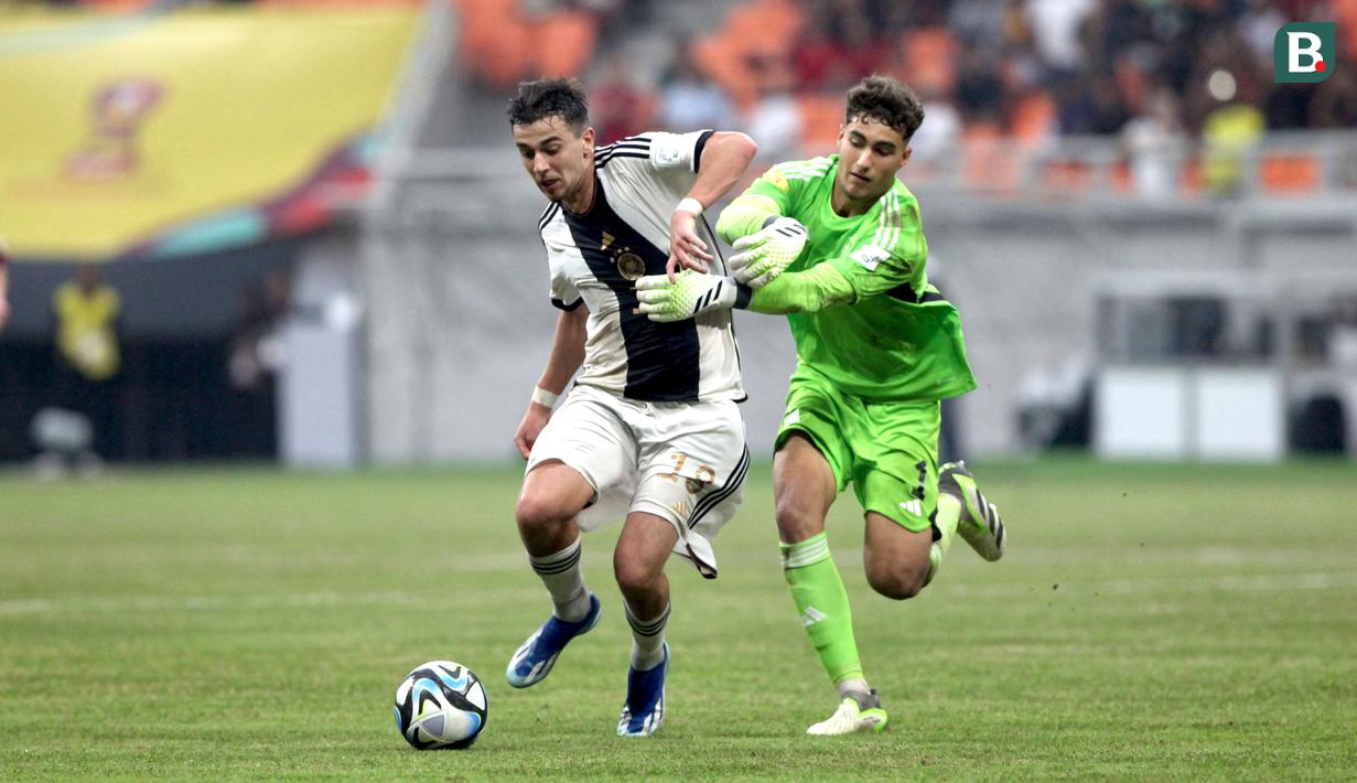 Kiper Timnas Spanyol U-17, Raul Jimenez (kanan), berusaha menghentikan laju dari pemain Jerman U-17 Bilal Yalcinkaya, saat pertandingan perempat final Piala Dunia U-17 2023 yang berlangsung di Jakarta International Stadium, Jumat (24/11/2023). Atas perbuatannya, Jimenez langsung diberikan hadiah berupa kartu merah oleh wasit. (Bola.com/Arief Bagus)