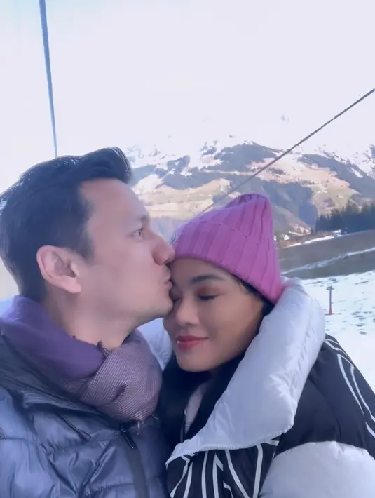 Tidak hanya membagikan momen harmonis, Titi Kamal juga membagikan momen romantis. Christian Sugino mencium kening sang istri saat berada di kereta gantung. [Instagram/titi_kamall]
