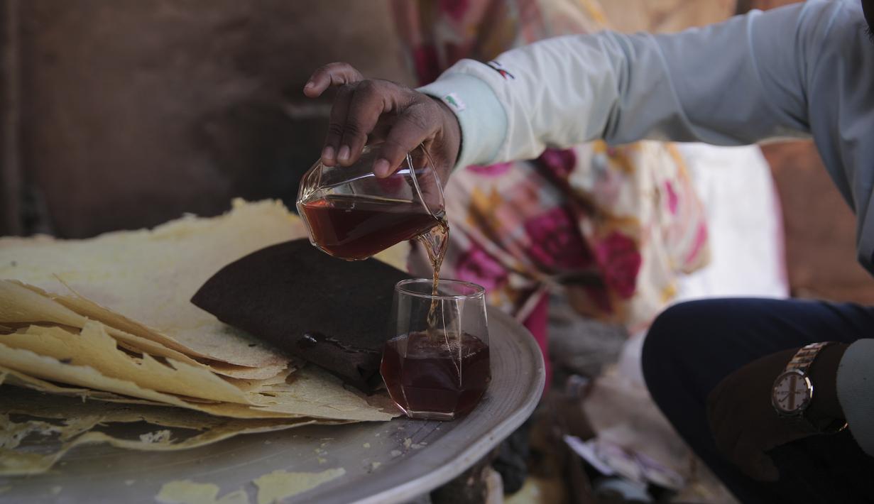 Seorang pria Sudan menuangkan segelas "helo-murr", minuman khas Ramadhan yang terbuat dari jagung kering dan rempah-rempah yang kemudian dicelupkan ke dalam air, di Khartoum, Sudan, pada 22 Maret 2023. (AP Photo/Marwan Ali)