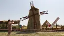 Pengunjung mengambil gambar kincir angin yang terbuat dari jerami di permukiman Krasnoye, Stavropol, Rusia, Rabu (19/7). Seluruh arena bermain pada taman tersebut terbuat dari tumpukan jerami. (REUTERS/Eduard Korniyenkov)