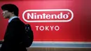 Seorang pria berjalan melewati logo Nintendo Co. Jepang yang dipajang di toko baru Nintendo di Tokyo, 19 November 2019. Nintendo akan meresmikan toko pertamanya di ibu kota Jepang tersebut pada pekan ini. (Behrouz MEHRI/AFP)