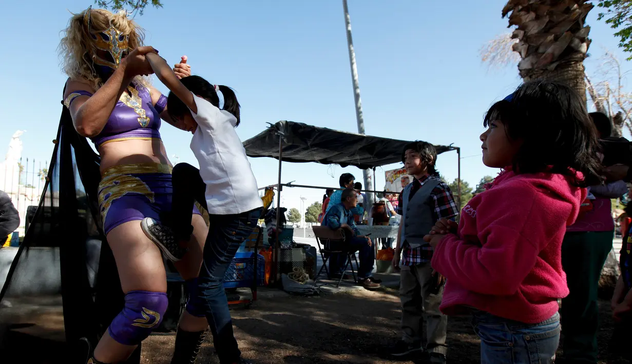 Pegulat Jerman 'Diosa del Rhin' (Dewi Rhin) bersama sejumlah bocah saat aksi kesetaraan gender di Ciudad Juarez, Meksiko (13/3/2016). Selain pegulat, Rhin juga merupakan seorang aktivis perempuan. (Reuters/Jose Luis Gonzalez)
