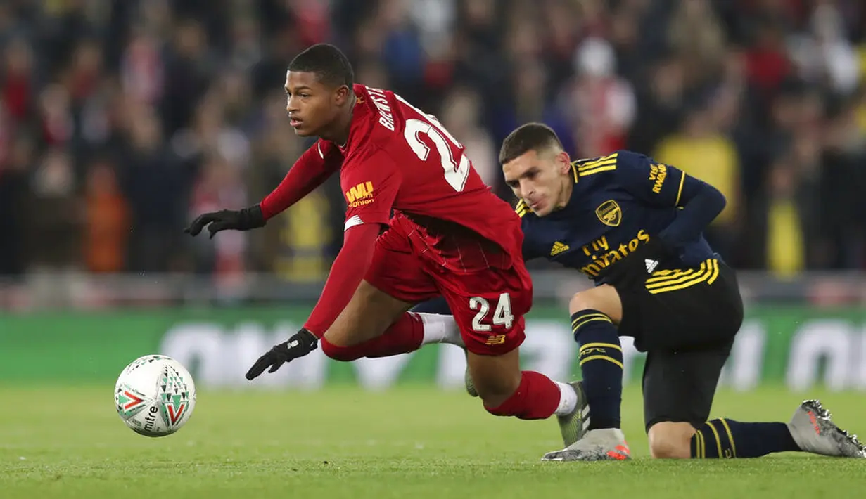 Pemain Liverpool, Rhian Brewster, terjatuh saat berebut bola dengan pemain Arsenal, Lucas Torreira, pada laga Piala Liga Inggris 2019 di Stadion Anfield, Rabu (30/10). Liverpool menang adu penalti atas Arsenal dengan skor 5-4. (AP/Jon Super)