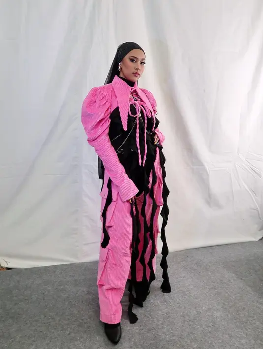 Jinan pernah manggung di F1 Night Race dengan busana hitam pink yang nyentrik. Outfit yang terdiri dari jumpsuit dengan detail kerah kerah dan lengan pleated serta rumbai hitam sebagai aksen. [@jinanlaetitia]