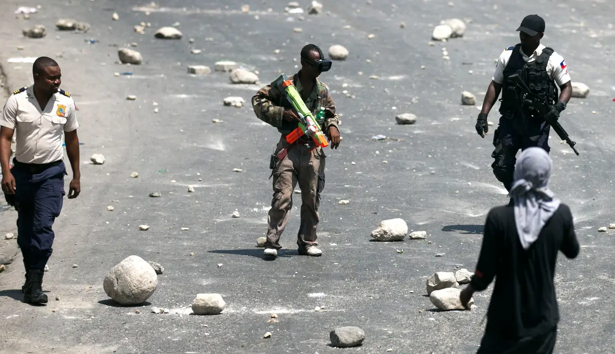 Seorang pengunjuk rasa membawa senjata mainan saat protes krisis bahan bakar di Port-au-Prince, Haiti, Senin (16/9/2019). Protes menyebabkan bank dan kantor pemerintahan tutup. (AP Photo/Dieu Nalio Chery)