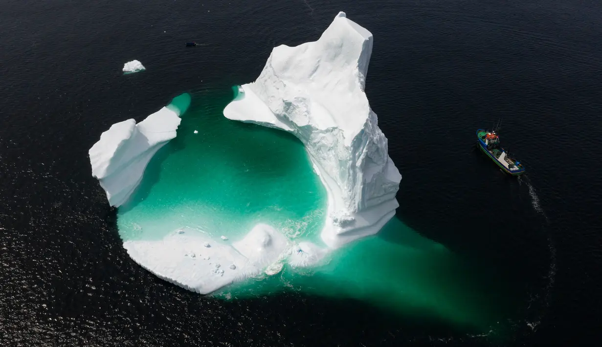 Kapal Kapten Edward Kean melewati gunung es terapung di Teluk Bonavista, Newfoundland, Kanada, 29 Juni 2019. Banyaknya gunung es terapung menjadikan Newfoundland destinasi wisata baru di Kanada. (Johannes Eisele/AFP)