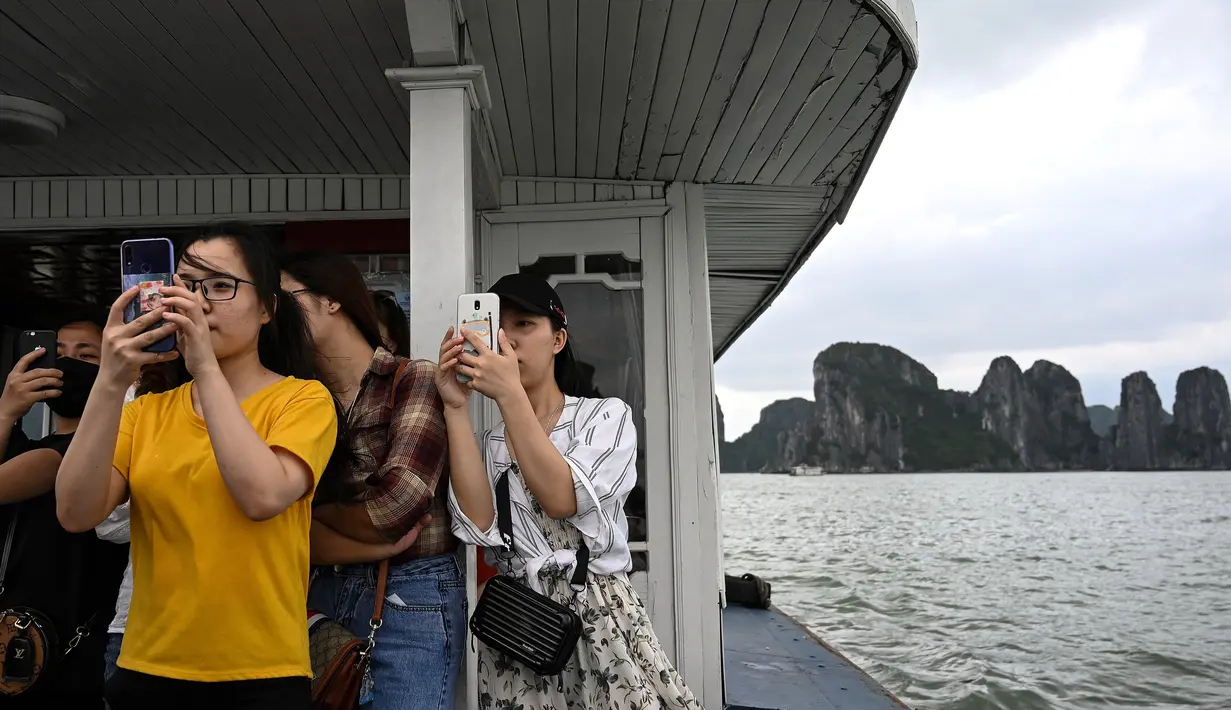 Wisatawan domestik menikmati suasana kawasan Ha Long Ba di atas kapal di Quang Ninh, Vietnam, (16/5/2020). Sempat terpukul akibat pandemi virus corona Covid-19, pariwisata Vietnam kembali menggeliat setelah otoritas setempat melonggarkan pembatasan perjalanan. (AFP/Manan Vatsyayana)
