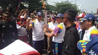 Obor Asian Games diserahkan ke Pj Bupati Purwakarta, M Taufiq Budi Santoso lalu diberikan kepada Torch Bearer, Kapolres Purwakarta AKBP Twedi Aditya Bennyahdi. (Liputan6.com/Cakrayuri Nuralam)