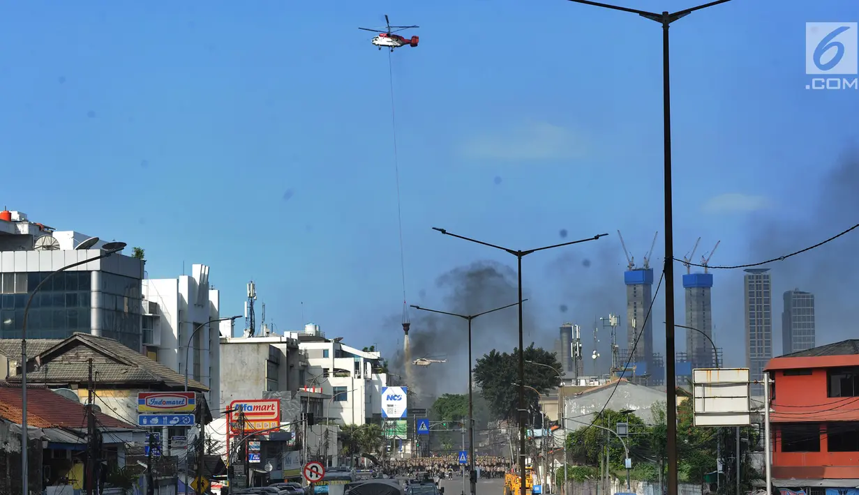 Helikopter water bombing menyiramkan air ke arah ban yang dibakar massa di kawasan Slipi, Jakarta, Rabu (22/5/2019). Air dijatuhkan dari udara ke arah api yang berasal dari ban bekas. (merdeka.com/Arie Basuki)