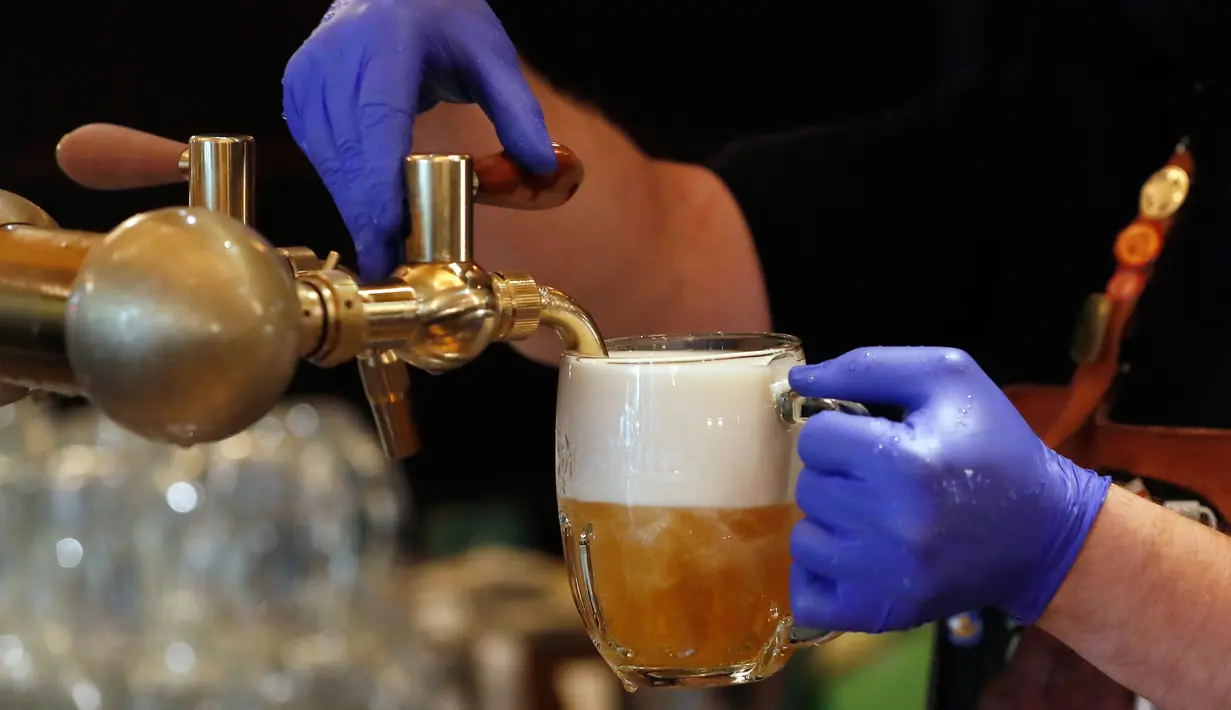 Bartender membuat bir di teras restoran di Praha, Republik Ceko, Senin, (11/5/2020). Bar, restoran, kafe yang menawarkan tempat duduk terbuka mulai melayani konsumen pertama mereka sejak 14 Maret. (AP/Petr David Josek)