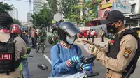 Salah seorang pekerja menunjukan surat tugas ke petugas kepolisian yang berjaga di lokasi penyekatan di Jalan Raya Margonda, Kota Depok. (Liputan6.com/Dicky Agung Prihanto)