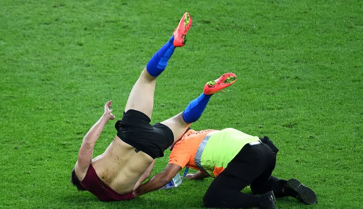 Petugas keamanan langsung mengejar dan menangkap fans nakal tersebut untuk segera diamankan, Brasil, Senin (14/07/2014) (AFP PHOTO/CHRISTOPHE SIMON)