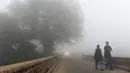 Pelajar India berjalan menuju sekolah saat kabut asap akibat polusi udara menyelimuti New Delhi, Rabu (8/11). Indian Medical Association menyarankan warga untuk tidak keluar rumah dan menghindari sedapat mungkin aktivitas fisik apapun. (PRAKASH SINGH/AFP)