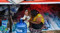 Seorang ibu dan anaknya duduk di tenda sebuah kamp sementara setelah gempa dan tsunami di Palu, Selasa (2/10). Data terbaru BNPB menunjukkan, korban tewas akibat tsunami dan gempa di Sulawesi Tengah sudah mencapai 1.347 orang. (AFP/JEWEL SAMAD)