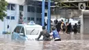 Sopir mendorong taksi untuk dipindahkan ke tempat lebih tinggi di Pool Blue Bird, Kramat Jati, Jakarta Timur, Rabu (1/1/2020). Banjir yang terjadi akibat hujan deras yang mengguyur Jakarta dan sekitarnya menyebabkan puluhan taksi dan belasan mobil terendam. (merdeka.com/Iqbal S. Nugroho)
