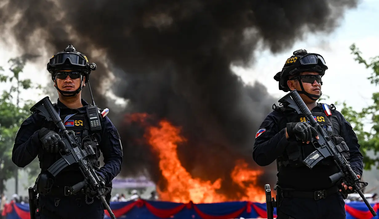 Petugas polisi militer Kamboja berjaga di depan tumpukan narkoba yang terbakar selama upacara penghancuran untuk memperingati "Hari Internasional Melawan Penyalahgunaan Narkoba dan Perdagangan Gelap" di Phnom Penh pada 28 Juni 2023.
(AFP/TANG CHHIN SOTHY)