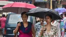 Dua orang wanita berjalan sambil menggunakan payung saat hujan mengguyur kota Gauhati, India, Selasa (30/5). Beberapa negara bagian di India timur laut mengalami hujan deras sebagai efek topan Mora yang melanda selatan Bangladesh. (AP Photo/ Anupam Nath)