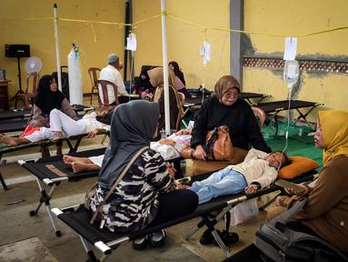 Murid-murid sekolah dasar mendapatkan perawatan di klinik darurat setelah mengalami keracunan usai menyantap makanan yang dibagikan lewat program Makan Bergizi Gratis di Bandung, Jawa Barat, pada 23 September 2025. (Timur Matahari/AFP)