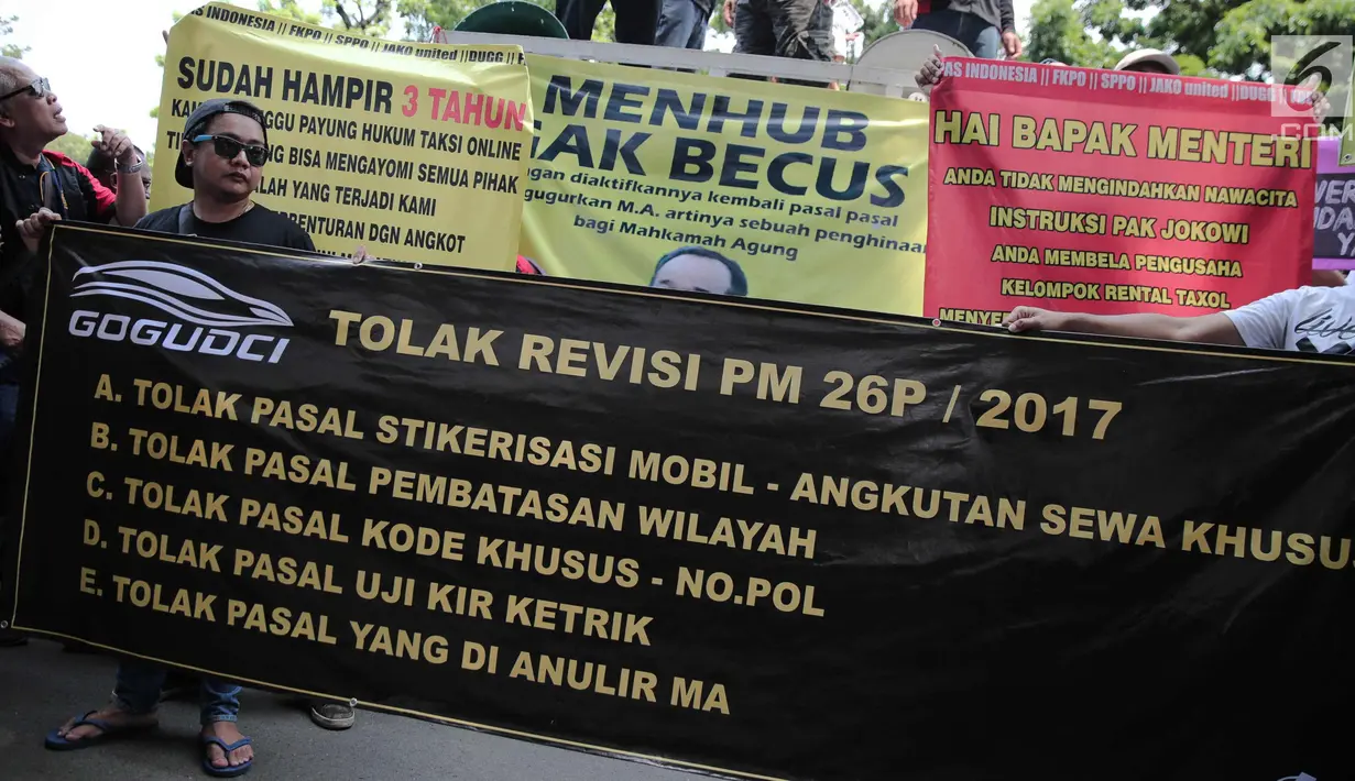 Pengemudi transportasi online membentangkan spanduk saat menggelar aksi di depan kantor Kementerian Perhubungan, Jakarta, Rabu (25/10). Dalam aksinya mereka menolak revisi PM 26P / 2017 terkait aturan taksi online. (Liputan6.com/Faizal Fanani)