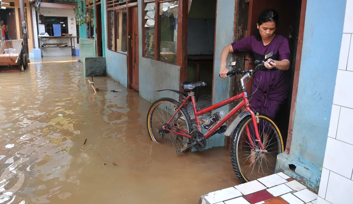 Warga memindahkan sepedanya menyusul surutnya air yang sempat merendam pemukiman mereka di kawasan Kampung Pulo, Kelurahan Kampung Melayu, Jatinegara, Jakarta, Selasa, (17/11). (Liputan6.com/Gempur M Surya)