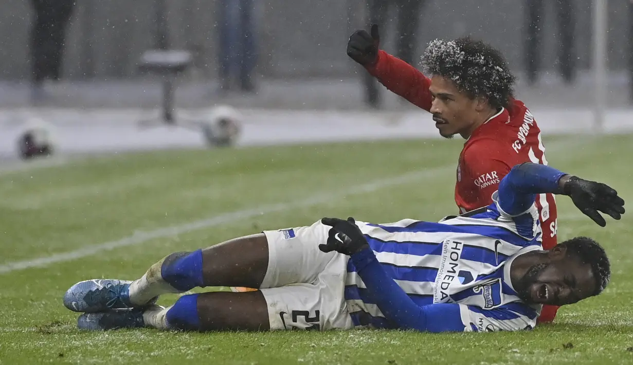 Bek Hertha Berlin, Jordan Torunarigha dan penyerang Bayern Munchen, Leroy Sane berbaring di atas lapangan setelah bertabrakan dalam lanjutan  Bundesliga di Olympiastadion, Sabtu (6/2/2021) dini hari WIB. Bayern Munich menang dengan skor 1-0 saat bertemu Hertha Berlin. (John MacDougall/pool via AP)