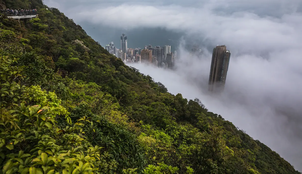 Orang-orang berkumpul di sudut pandang Peak untuk menyaksikan kabut di atas Hong Kong, Selasa (22/3/2022). Kabut tebal menyelimuti Hong Kong pada musim semi ketika wilayah tersebut dipengaruhi oleh udara dingin dan hangat bergantian. (AFP/Dale De La Rey)