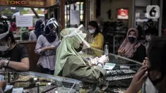 Pedagang mengenakan masker dan pelindung wajah saat melayani pembeli di  Pasar Kebayoran Lama, Jakarta Selatan, Senin (22/6/2020). Pasar Kebayoran Lama kembali buka setelah sebelumnya tutup selama tiga hari sejak 18 Juni 2020 akibat 14 pedagang positif COVID-19. (Liputan6.com/Faizal Fanani)