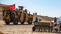 Warga lokal Suriah menyaksikan kendaraan militer Turki dan AS patroli gabungan di Desa al-Hashisha, Tal Abyad, Suriah, Minggu (8/9/2019). Pasukan Kurdi Suriah sendiri mulai menarik diri dari sepanjang perbatasan Turki pada akhir Agustus. (DELIL SOULEIMAN/AFP)