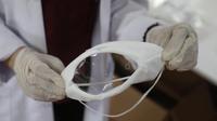 Seorang pekerja menunjukkan masker transparan di Istanbul, Turki, Rabu (27/5/2020). Kota Avcilar baru-baru ini memutuskan untuk memproduksi masker wajah yang dirancang khusus bagi kaum tunarungu di tengah pandemi COVID-19. (Xinhua/Osman Orsal)