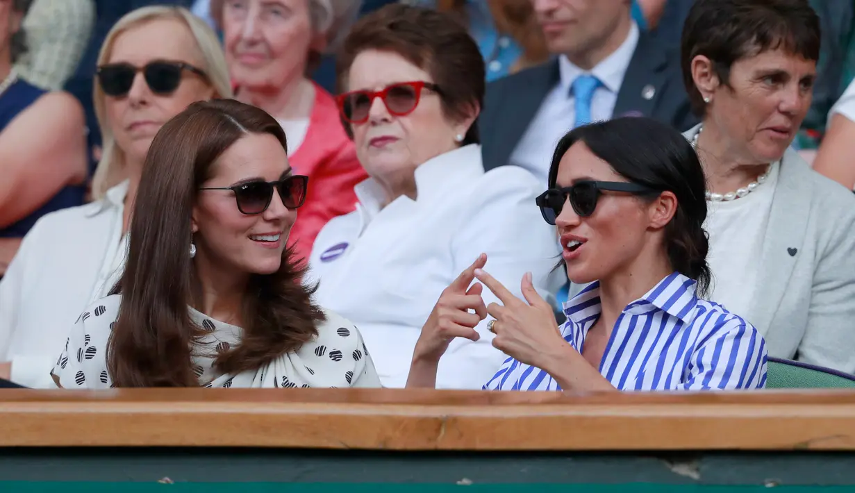 Duchess of Cambridge Kate Middleton dan Duchess of Sussex Meghan Markle berbincang saat menyaksikan pertandingan tenis dalam Kejuaraan Wimbledon di London, Inggris, (14/7). (AP Photo/Andrew Couldridge)