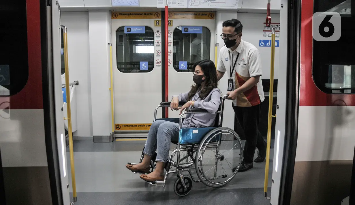 Petugas Light Rail Transit (LRT) Jakarta membantu mendorong kursi roda penumpang disabilitas dalam rangkaian gerbong kereta menggunakan kursi roda di Stasiun Pegangsaan Dua, Jakarta Utara, Selasa (24/1/2023). LRT Jakarta melakukan kampanye #NyamankanJakarta. (merdeka.com/Iqbal S. Nugroho)