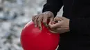 Ogun Sever Okur, pria Turki berusia 38 tahun mengikat balon untuk menggantungnya di puing-puing bangunan yang runtuh di Antakya, Turki selatan pada 21 Februari 2023, menyusul gempa berkekuatan 6,4 yang melanda pada 20 Februari, dua minggu setelahnya. gempa berkekuatan 7,8 melanda dekat Gaziantep dan telah menewaskan lebih dari 44.000 orang. (AFP/Sameer Al-Doumy)